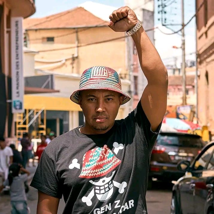 Herizo Andriamanantena, poing levé, coiffé d'un bob tressé, dans une rue de Madagascar